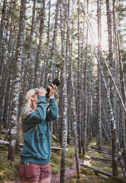 Woman photographer with telephoto lens in a forest