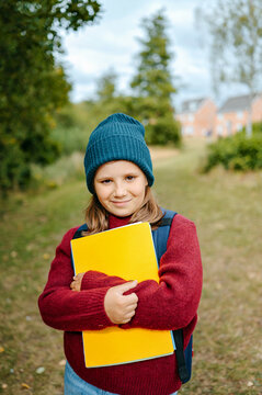 Girl holding a notebook outdoors before returning to school