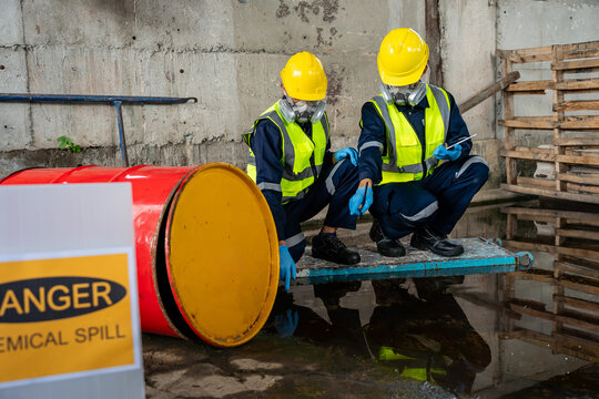 Occupational health and safety team assessing a toxic chemical spill near a danger sign and red barrel, recording data for environmental risk management and industrial accident prevention.