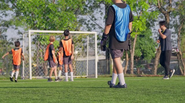 Group of young boys playing football together on outdoor soccer field. 