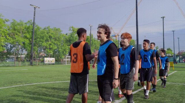 Two teams of diverse football players touching hands before soccer match. 
