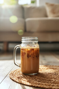 Iced coffee in mason jar on woven coaster by sofa