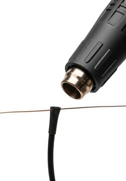 Detail shot of a heat gun shrinking tubing over a wire for electrical insulation and connection