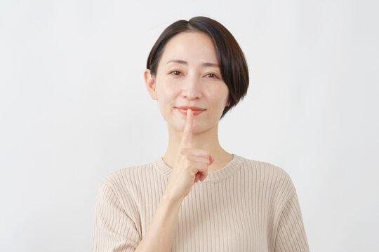 静かにと伝える女性　ミドルエイジ　白背景