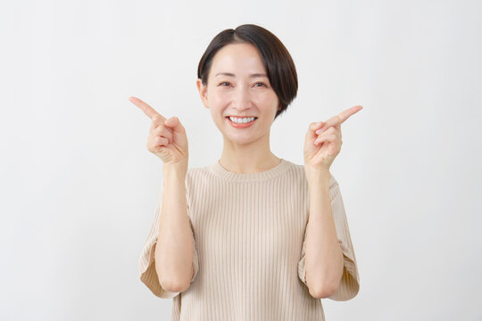 両手で指し示す笑顔の女性　白背景