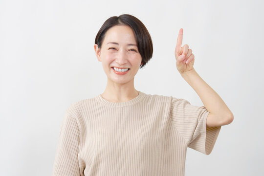 上を指差す笑顔の女性　ミドルエイジ　白背景