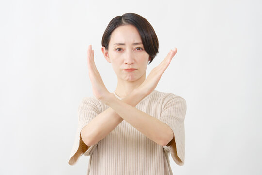 腕で大きなバツをつくる女性　白背景