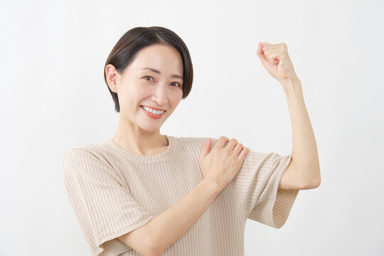 腕に力を込める笑顔の女性　白背景