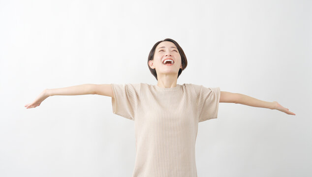 両腕を広げて深呼吸する女性　白背景