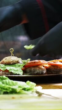 Chief on commercial kitchen serves burgers on the plate - inside the restaurant