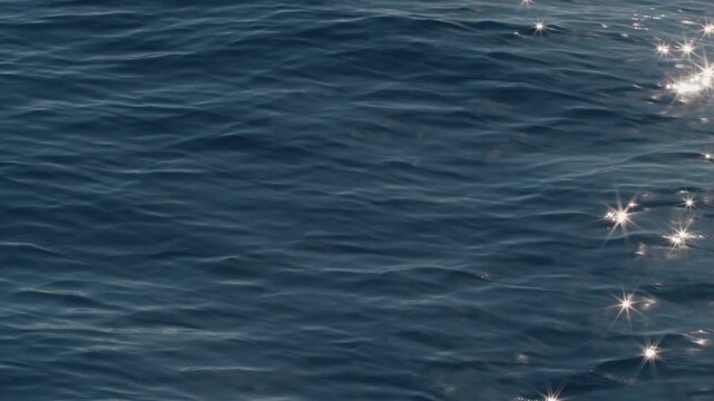 Sea surface with blinking stars and flares as seen from the moving sailing boat