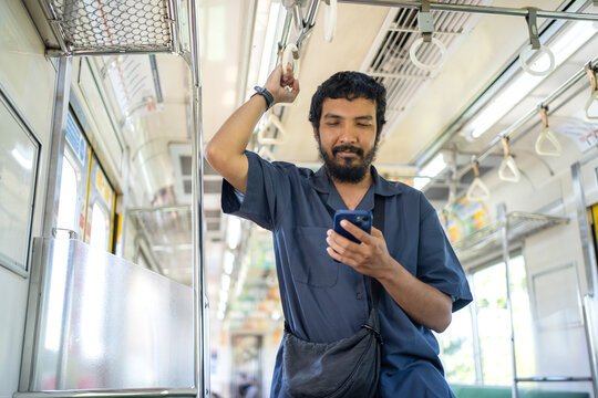 Indonesian Man Using Smartphone While Standing Inside KRL Train