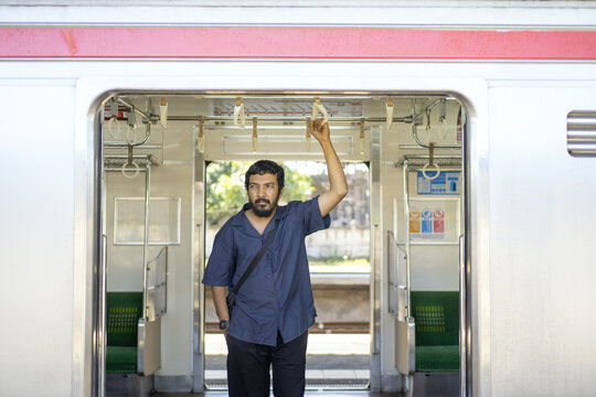 Indonesian Commuter Standing Inside Open KRL Train Door
