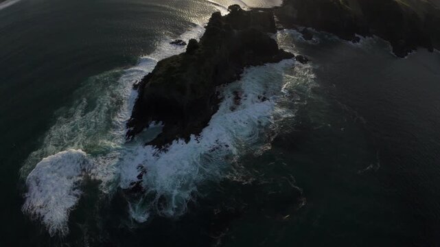 Low aerial flight along the rugged coastline of Great Barrier Island, New Zealand, revealing dramatic cliffs, ocean waves and untouched coastal landscape.
