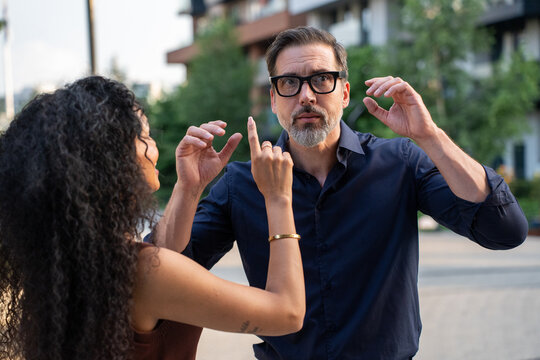 Man exploring AR glasses while woman observing city view outdoors