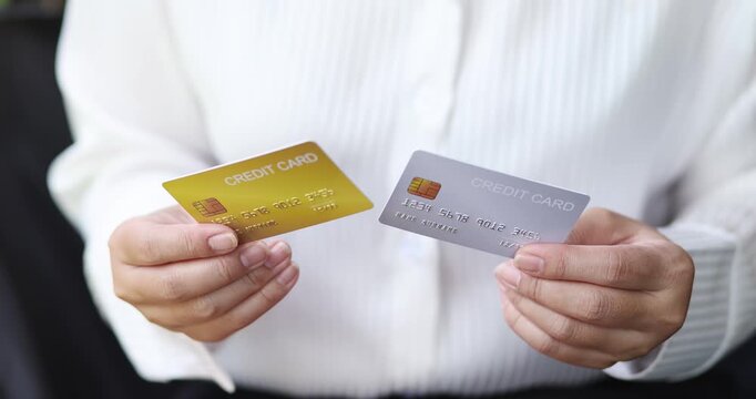 Woman holding two credit cards comparing payment options, banking, personal finance, online shopping, digital transactions, cashback, rewards, and financial decision concept