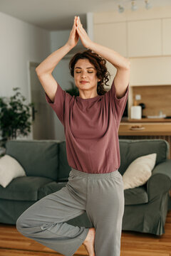 Woman practicing yoga tree pose meditation at home