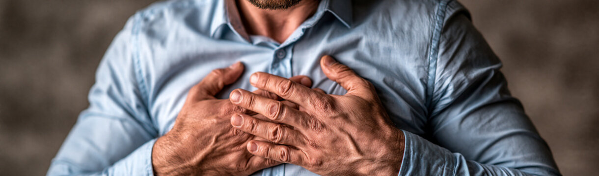 Chest Pain Distress: A man clutches his chest in discomfort, conveying a palpable sense of pain and worry. The tight focus on his hands and shirt emphasizes the intensity of his suffering.
