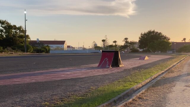 Skate park featuring ramps and obstacles under a golden evening sky, capturing urban recreation and a peaceful lifestyle scene