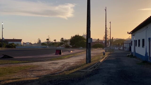 Alentejo rural landscape with skate park obstacles and street light poles silhouetted against a warm glowing sunset sky