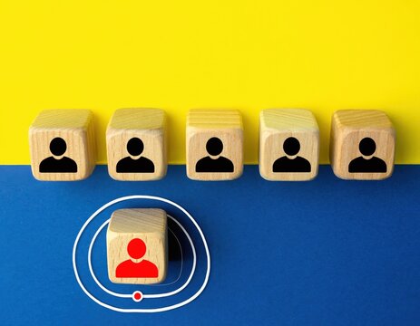 Wooden cubes with black human icons and one red human icon on blue and yellow background, concept of leadership and selection