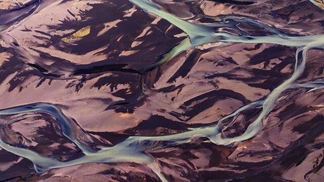 A mesmerizing top-down aerial view of a braided river in Iceland. Milky glacial meltwater weaves intricate, vein-like patterns through dark volcanic sand, highlighting the raw beauty of the Icelandic