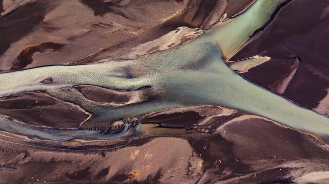 Abstract aerial perspective of Icelandic glacial streams branching and rejoining. The dynamic flow of the meltwater carves constantly shifting channels through the volcanic earth.