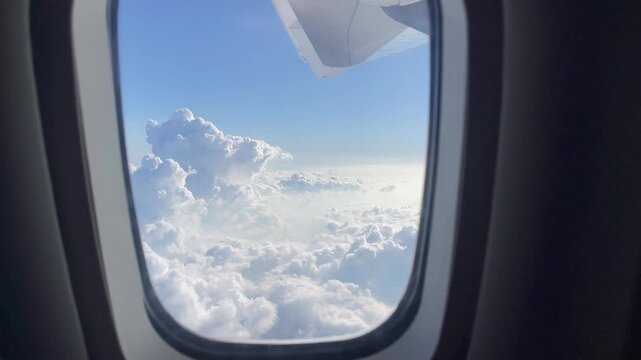 Clouds and airplane wing seen through a passenger window