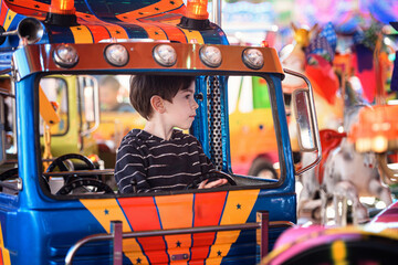 Profile view of young boy in blue carousel toy truck looking to the side © Oleksii Yemelianov