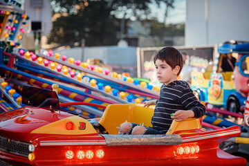 Thoughtful child riding in a red illuminated car on amusement park carousel © Oleksii Yemelianov
