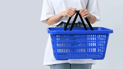 Fototapeta premium Shopping Basket Ready: A person holding a vibrant blue plastic shopping basket, poised for a shopping trip or a day of errands, symbolizing commerce and consumerism.