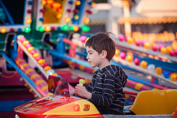 Child holding control lever on fairground carousel with colorful bokeh background © Oleksii Yemelianov