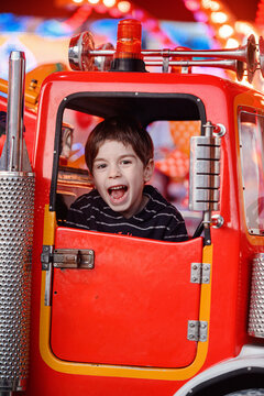 Intensely screaming boy inside red car ride frame close up portrait funfair