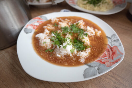 A plate of tomato soup with rice.

