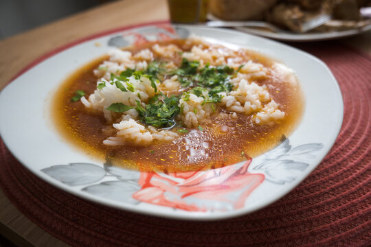 A plate of tomato soup with rice.
