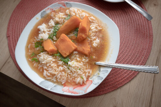 A plate of tomato soup with rice.
