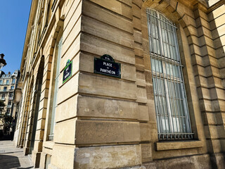 Obraz premium Sunlit stone facade at Place du Panthéon corner in Paris, France showing arched windows and neoclassical architecture on a clear blue day