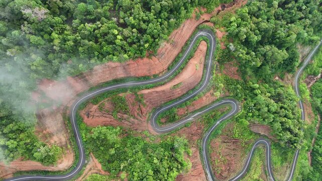 Aerial Drone Ascending While Orbiting Above Winding Mountain Road Through Lush Tropical Forest
