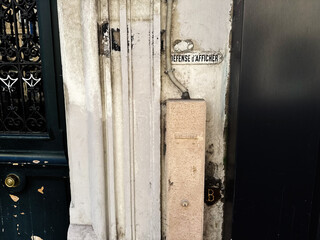 Obraz premium Weathered doorway and vintage sign on a Paris, France building wall with textured plaster and metal gate detail
