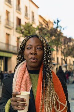 Young black woman enjoying coffee in city street