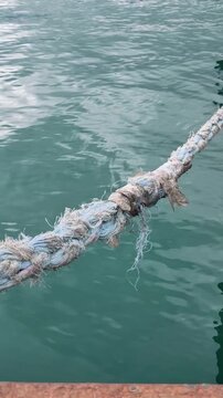 Close-up of a thick marine rope stretched above turquoise seawater.
