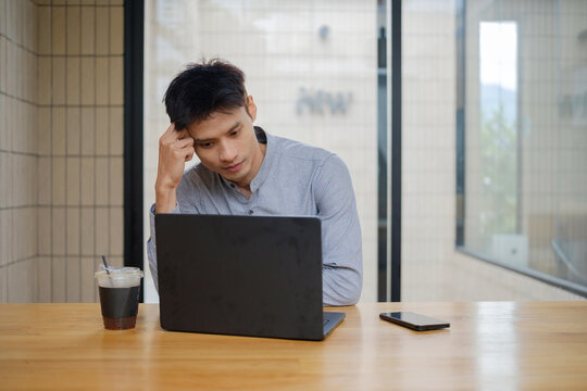 Businessman working seriously on laptop in a modern cafe workspace, business planning and remote work concept.
