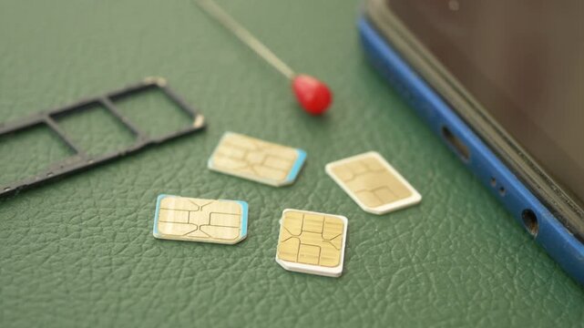 Close up of SIM cards and smartphone tray on textured green surface for mobile technology concept