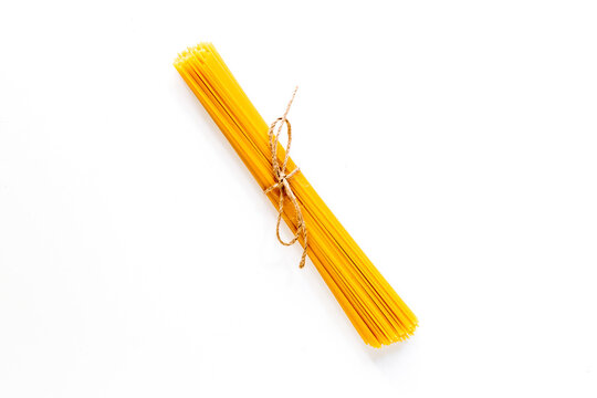 Bunch of spaghetti tied with rope on white background top view copyspace