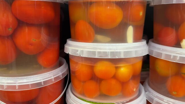 Fresh cherry tomatoes and garlic cloves in transparent containers with liquid, suitable as background