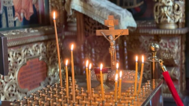 Orthodox church altar scene with lit candles and golden religious icons in the background
