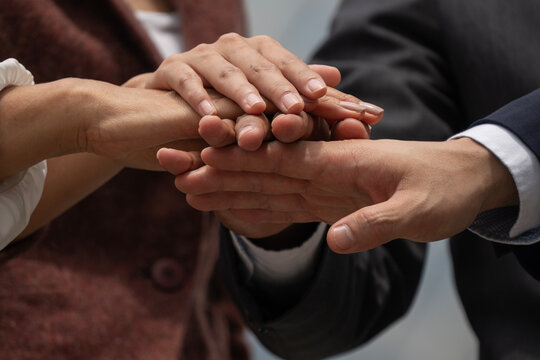 Close-up of diverse business team stacking hands together in unity. Corporate professionals showing support, partnership, and successful teamwork commitment.