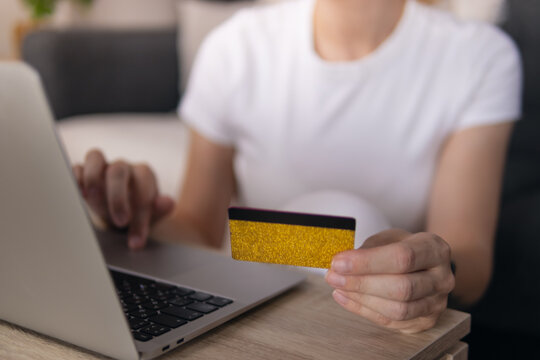 Person doing online shopping using laptop and holding credit card for secure e-commerce payment, enjoying convenient mobile banking and digital transaction from home