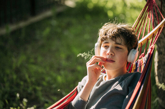 Teenager relaxing in a hammock outdoors listening to music