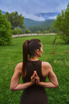Woman practices yoga outdoors in nature with mountain background